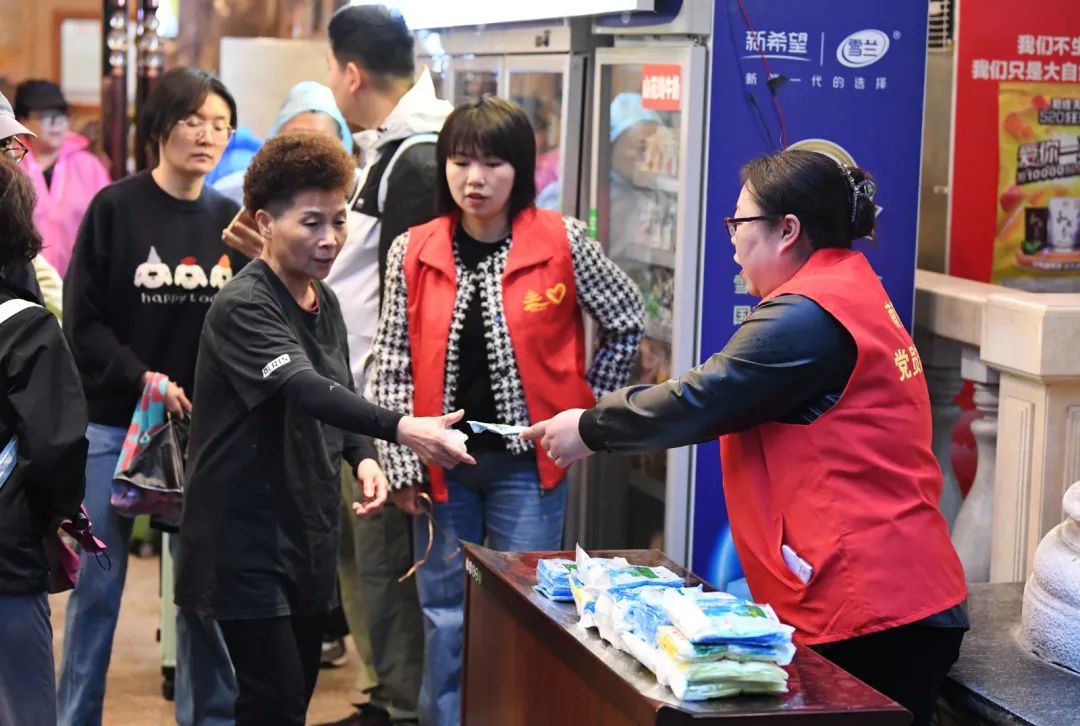 4月24日,在贵阳市南明区花果园,社区志愿者正在为出行的游客发放一次性雨衣。2 图片